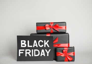 Photo of Gift boxes and sheet of paper with words Black Friday on light grey background