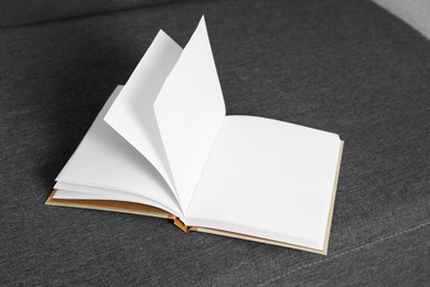 Open blank hardcover book on grey sofa
