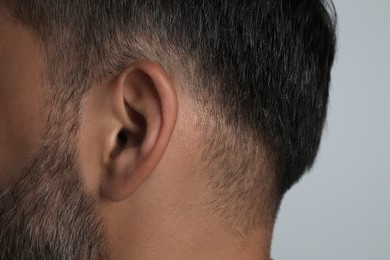 Man on light grey background, closeup of ear