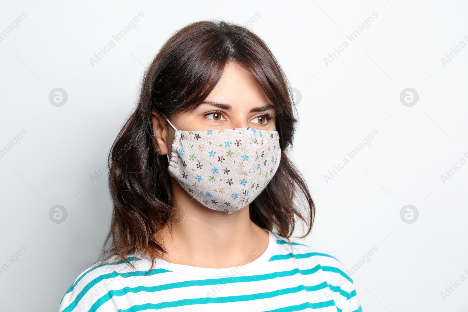 Photo of Young woman in protective face mask on light background