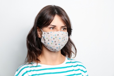 Young woman in protective face mask on light background