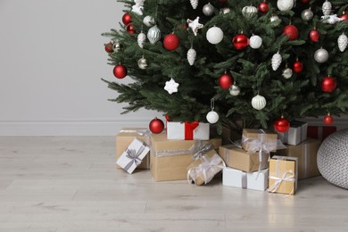 Photo of Beautifully decorated Christmas tree and many gift boxes in room, space for text