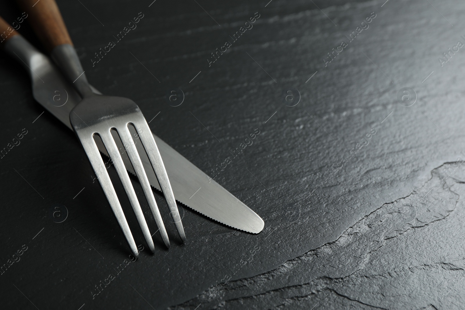 Photo of Stylish cutlery on black table, closeup. Space for text