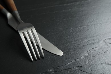 Photo of Stylish cutlery on black table, closeup. Space for text