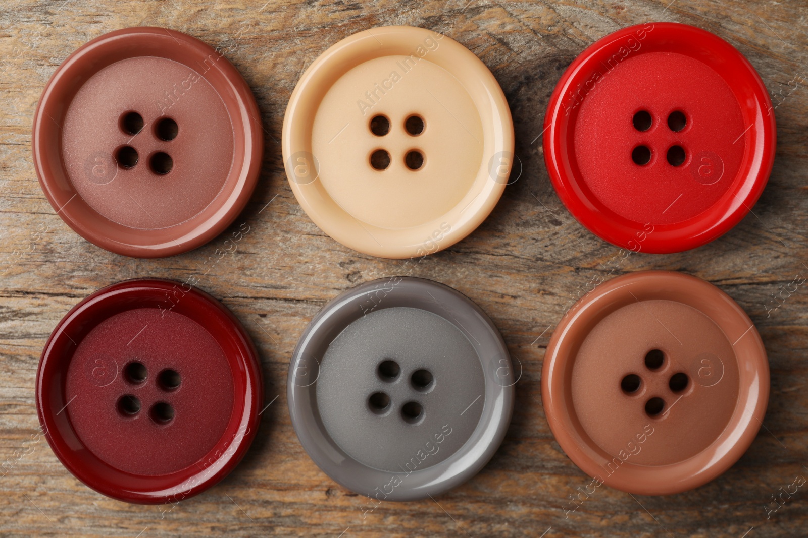 Photo of Many plastic sewing buttons on wooden background, flat lay