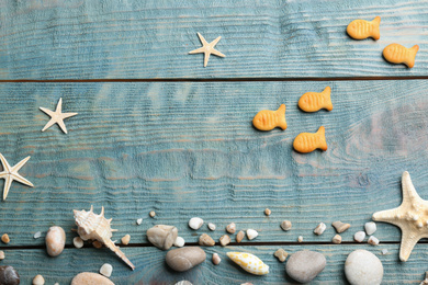 Photo of Underwater life represented with goldfish crackers on light blue wooden table, flat lay
