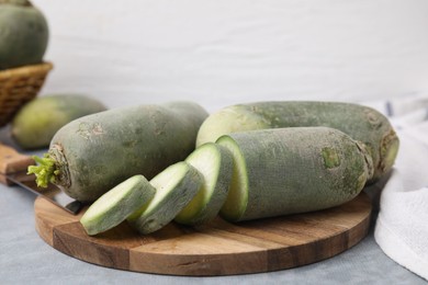 Photo of Green daikon radishes and knife on light grey table