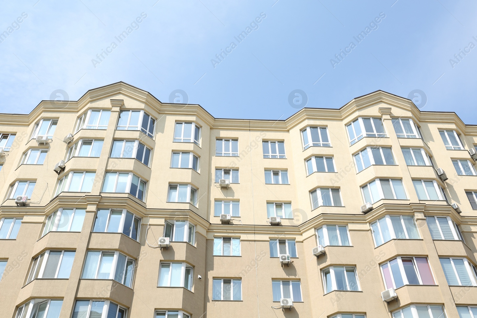 Photo of Exterior of multi storey apartment building against blue sky, low angle view