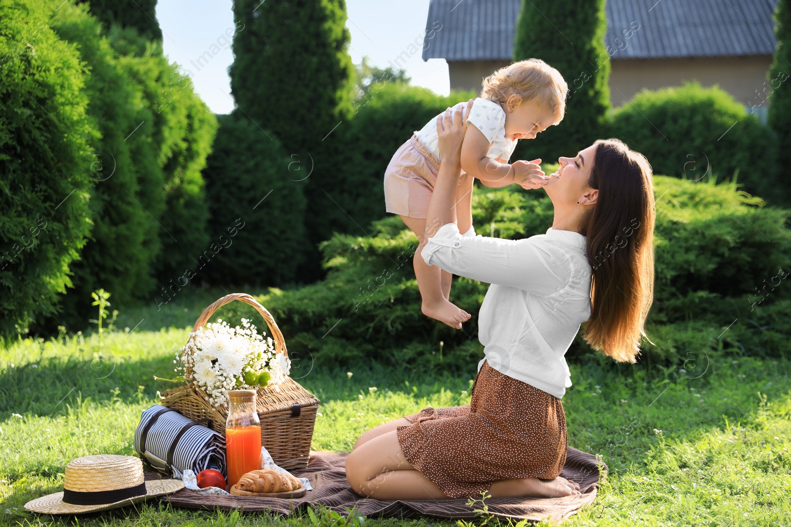 Photo of Mother and her baby daughter playing while having picnic in garden on sunny day