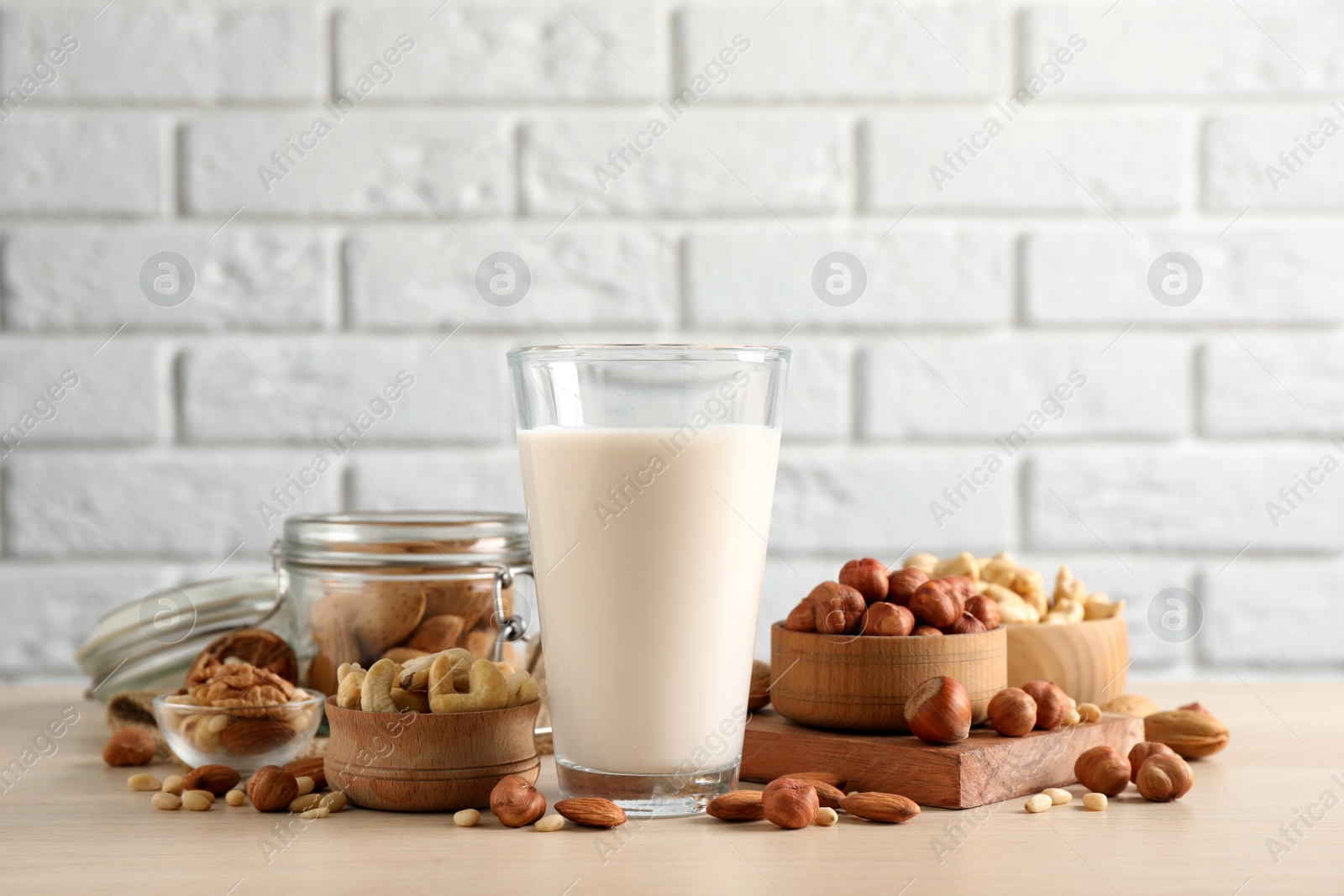 Photo of Vegan milk and different nuts on wooden table