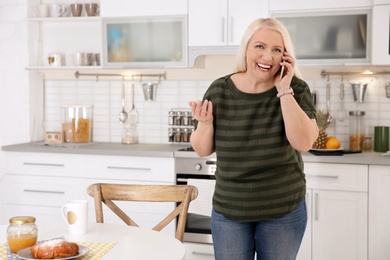 Mature woman talking on mobile phone at home