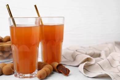 Photo of Tamarind juice and fresh fruits on white table, space for text