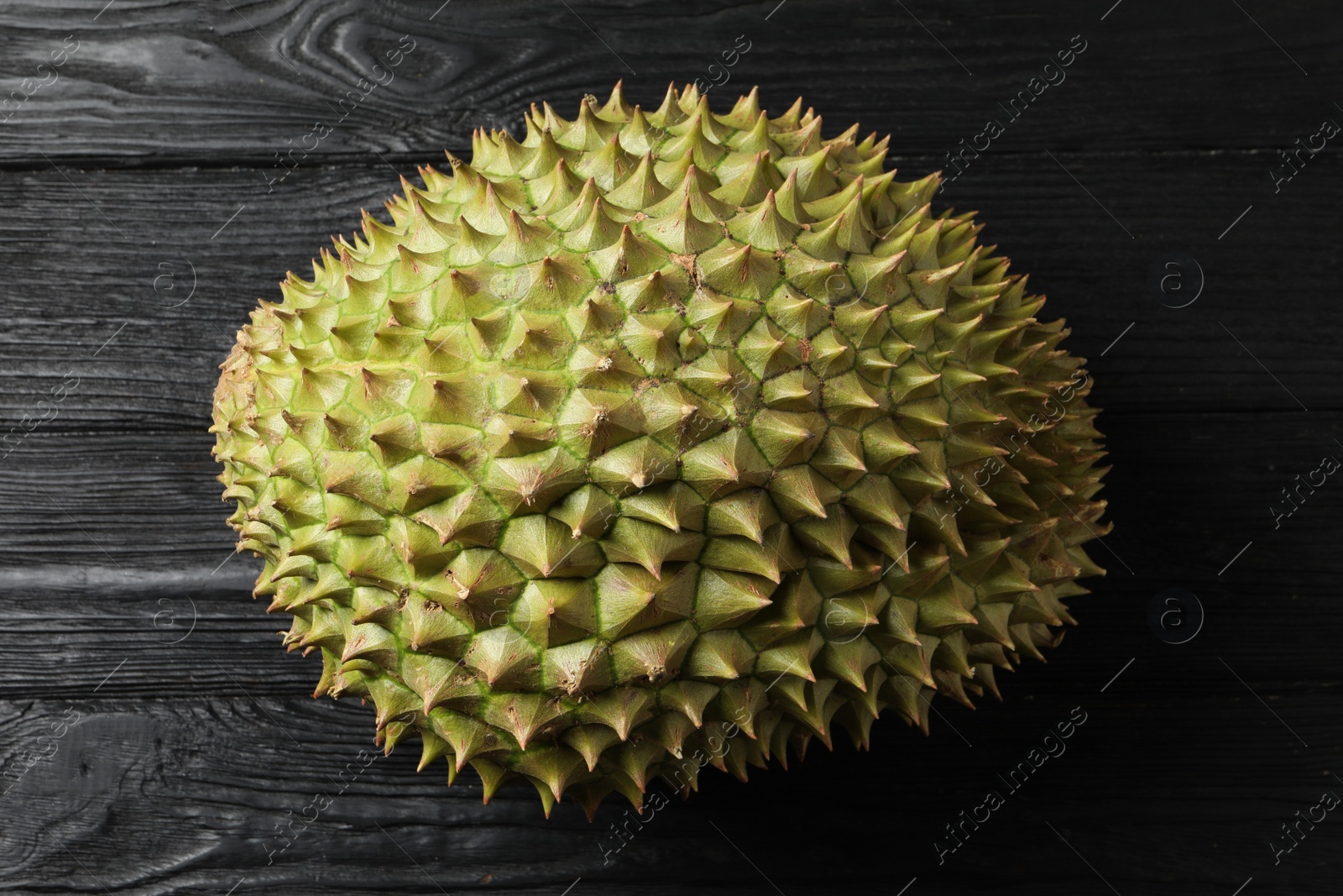 Photo of Ripe durian on black wooden table, top view