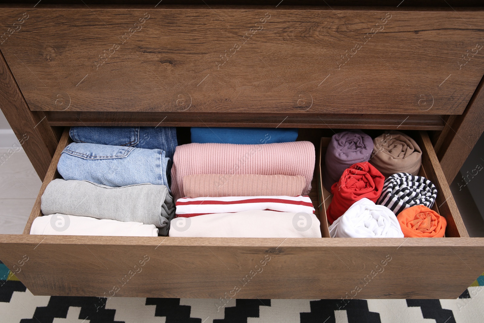 Photo of Open drawer with folded clothes indoors. Vertical storage of clothing