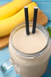 Photo of Mason jar with banana smoothie on light blue wooden table, closeup