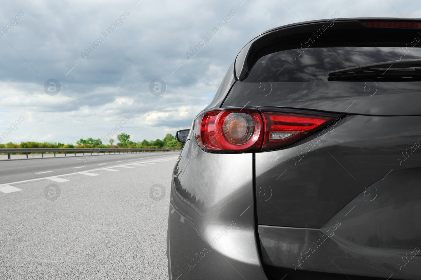 Photo of New black modern car on asphalt road, closeup of taillight