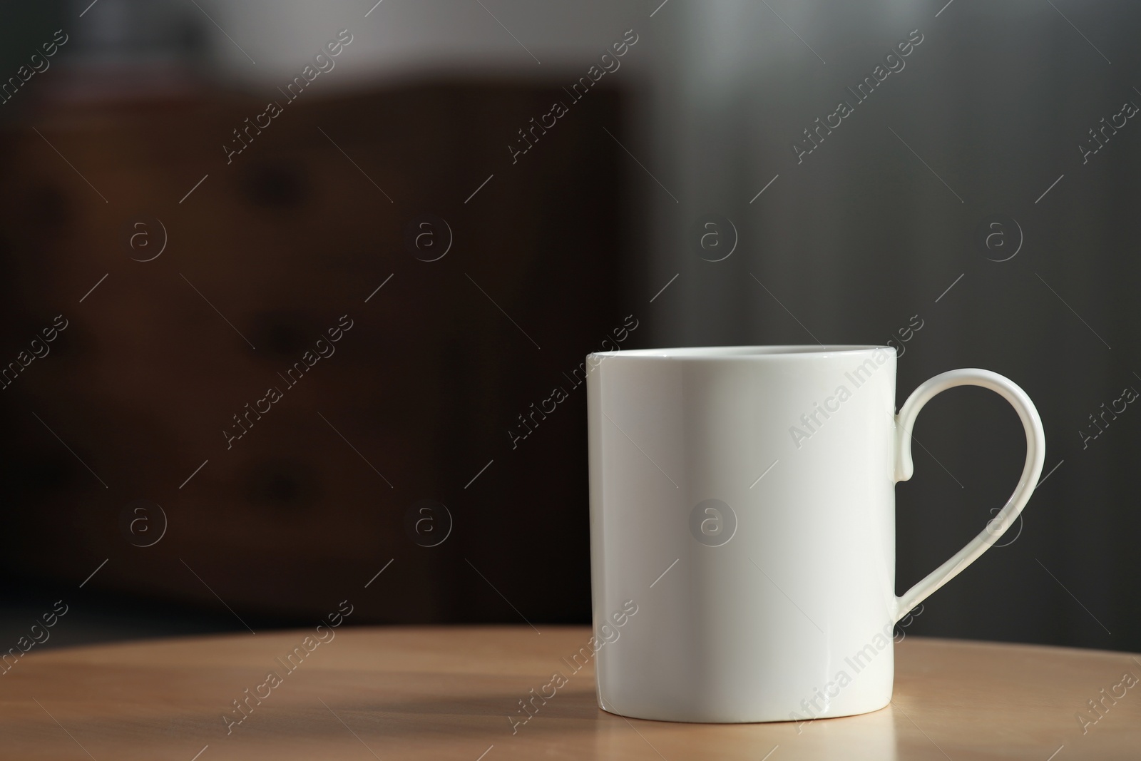 Photo of White mug on wooden table indoors. Mockup for design