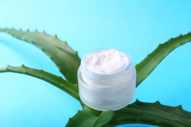 Photo of Aloe leaves and cosmetic product on light blue background