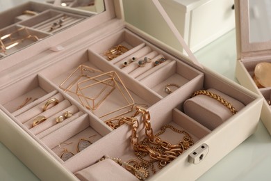 Jewelry box with stylish golden bijouterie on white table, closeup