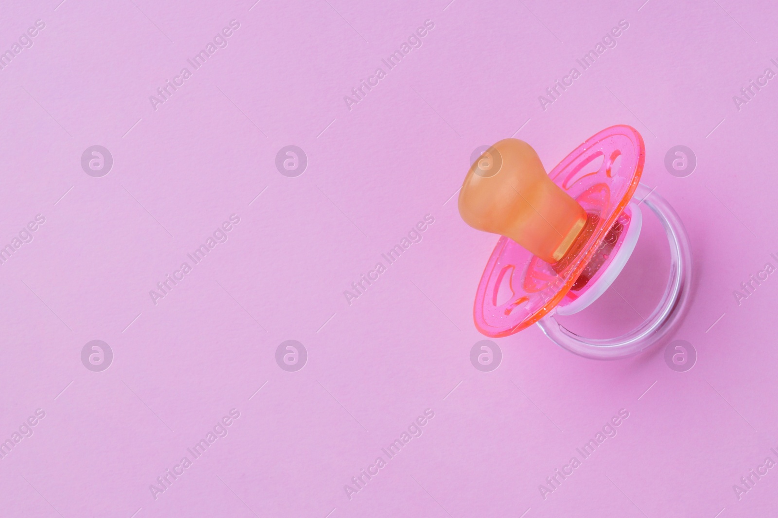 Photo of New baby pacifier on pink background, top view. Space for text