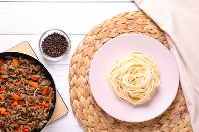 Photo of Delicious spaghetti, minced meat with carrot and pepper on white wooden table, flat lay