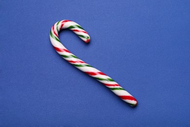 Photo of Sweet Christmas candy cane on blue background, top view