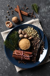 Different aromatic spices and fir branches on grey textured table, flat lay