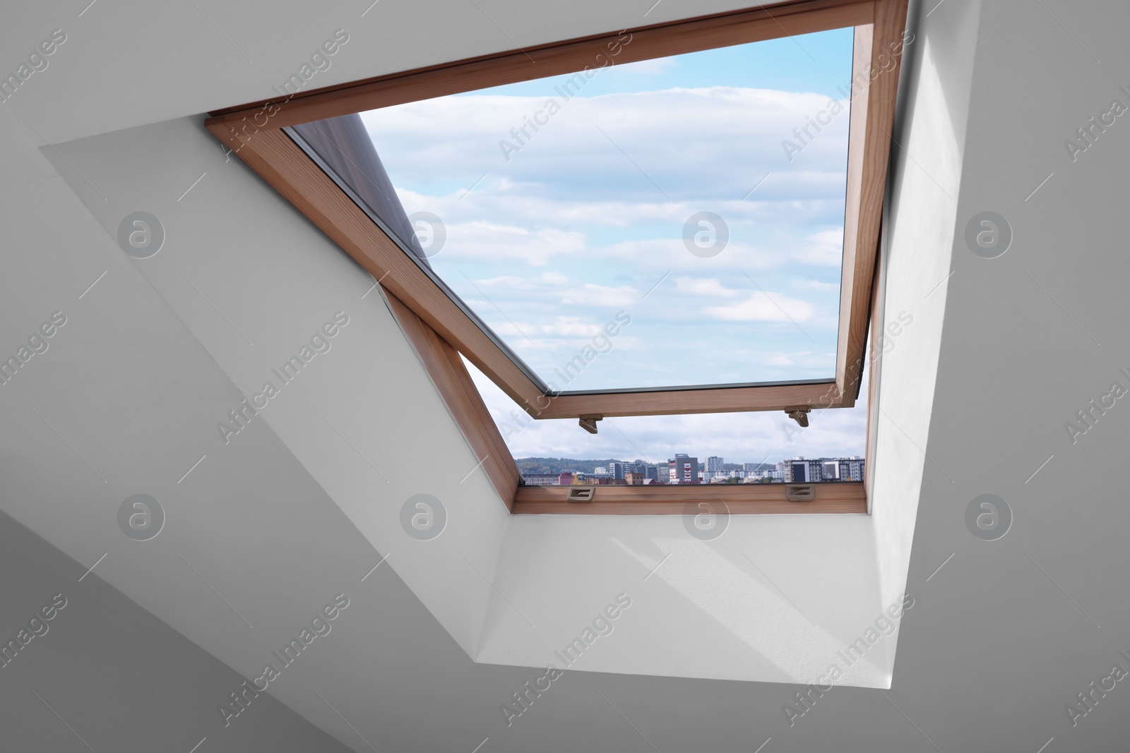 Photo of Open skylight roof window on slanted ceiling in attic room