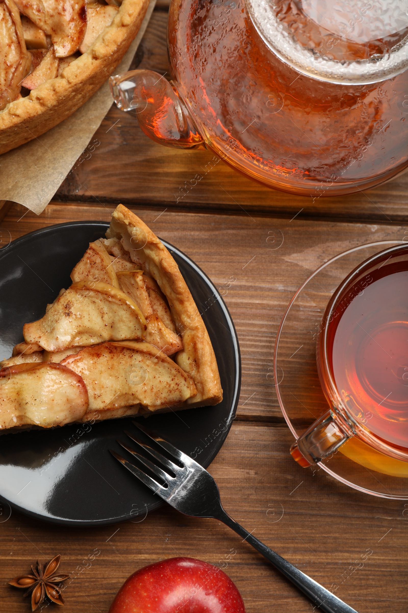 Photo of Delicious apple pie served with tea on wooden table, flat lay