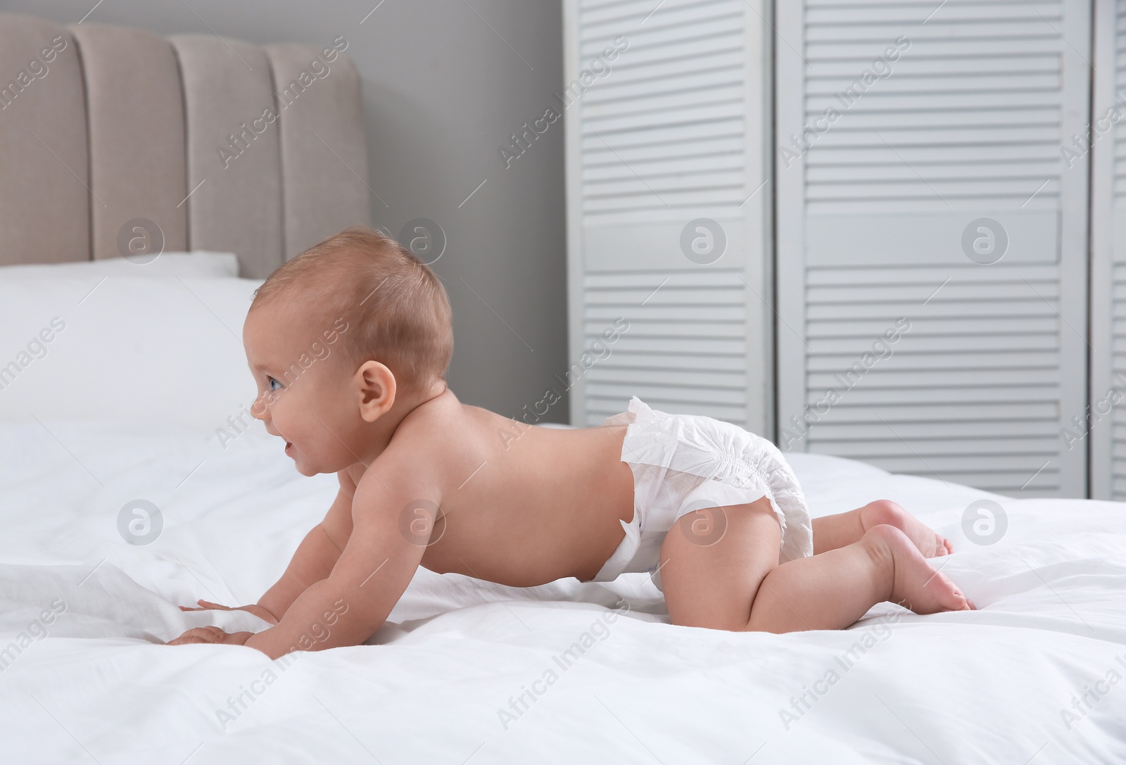 Photo of Cute baby in dry soft diaper on white bed at home