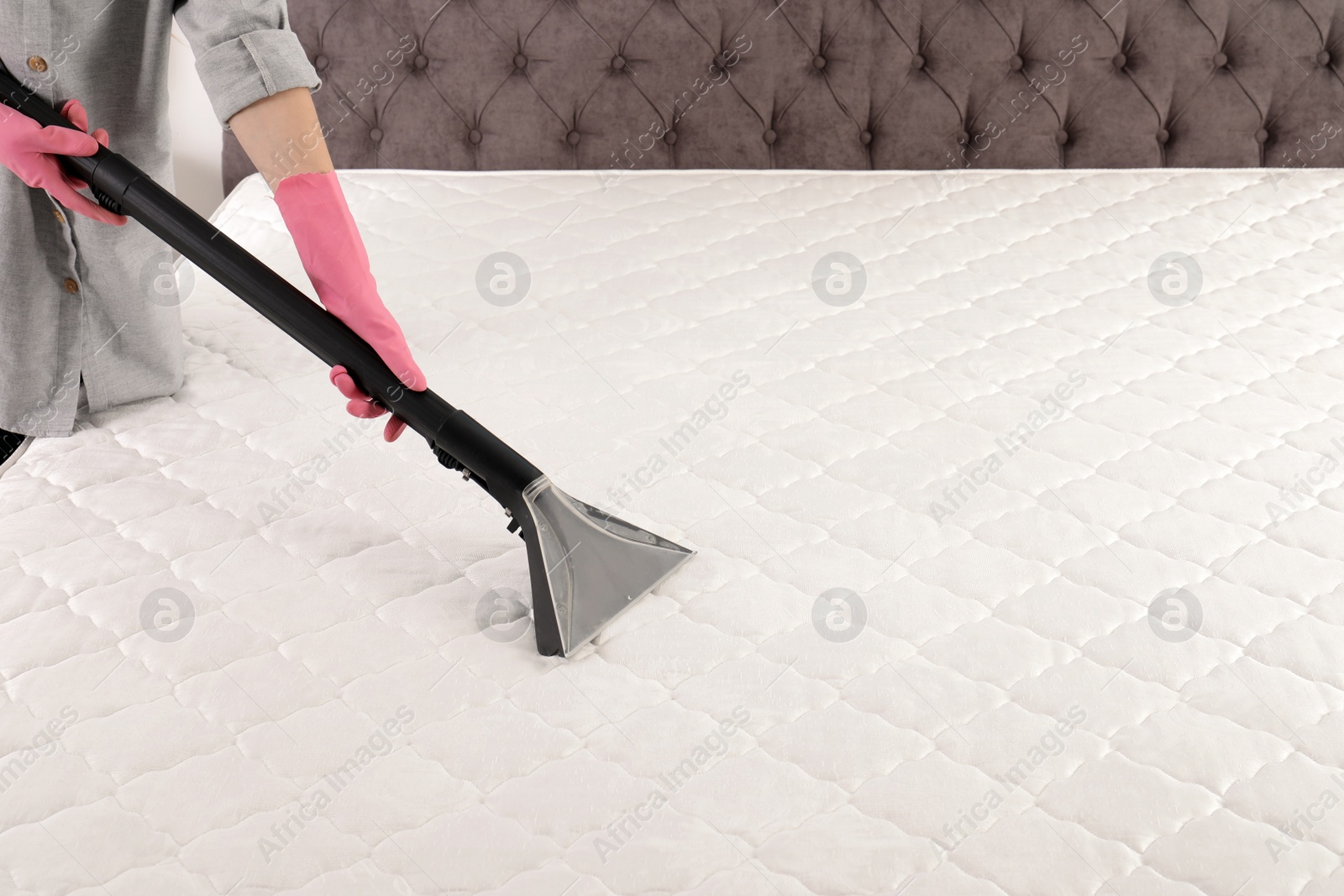 Photo of Woman disinfecting mattress with vacuum cleaner, closeup. Space for text