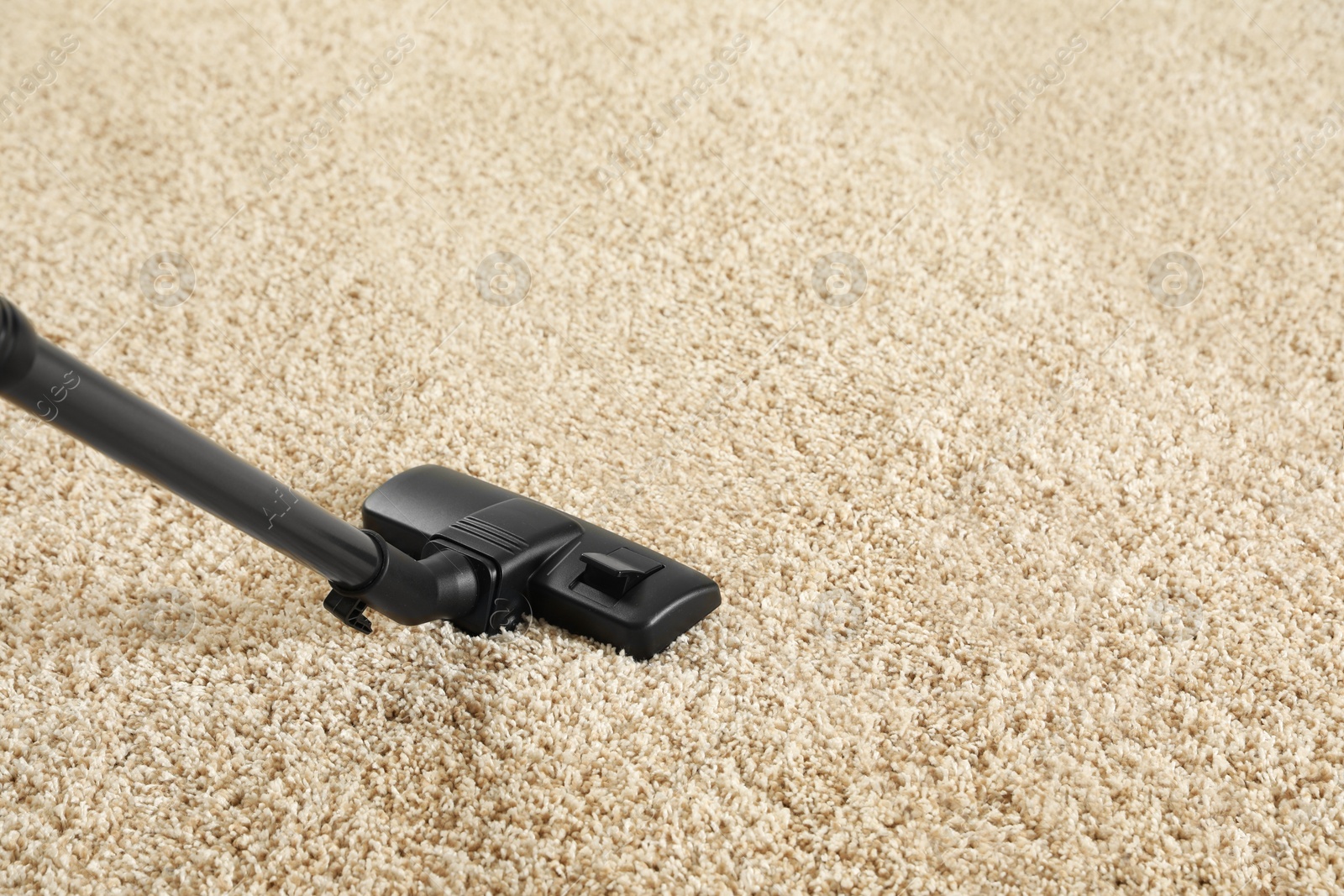 Photo of Removing dirt from beige carpet with modern vacuum cleaner. Space for text