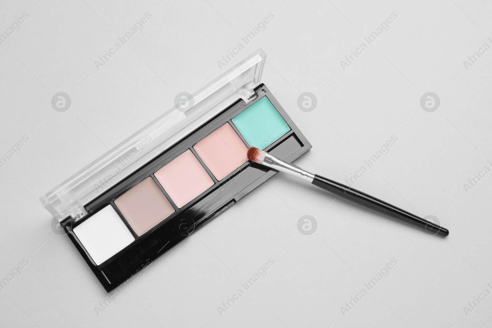 Photo of Colorful contouring palette with brush on white background, top view. Professional cosmetic product