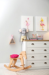 Photo of Chest of drawers and beautiful pictures in children's room. Interior design