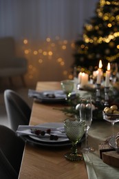 Photo of Christmas table setting with festive decor and dishware indoors