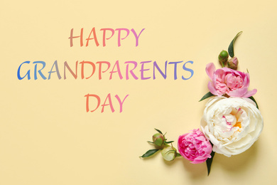 Image of Beautiful peonies and phrase HAPPY GRANDPARENTS DAY on color background, flat lay