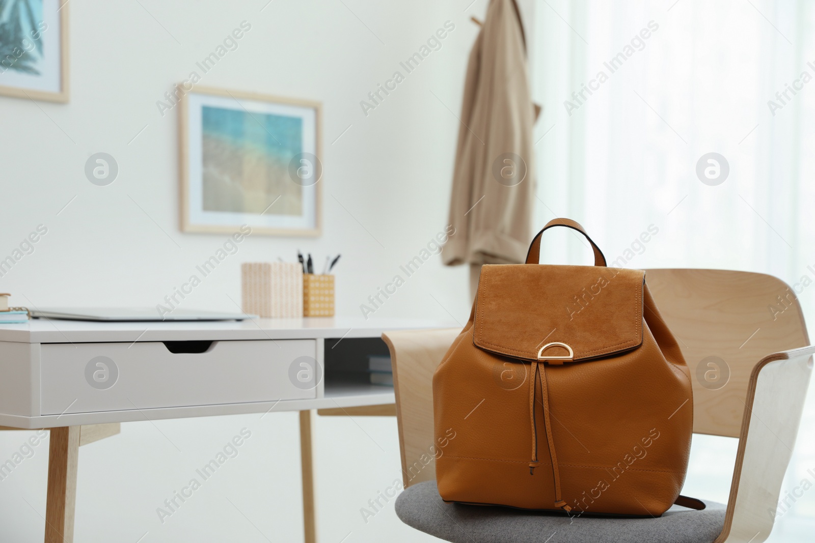 Photo of Stylish urban backpack on chair in room