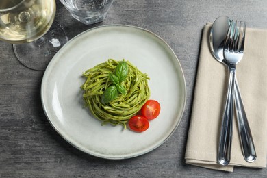 Photo of Tasty tagliatelle with spinach and tomatoes served on grey table, flat lay. Exquisite presentation of pasta dish