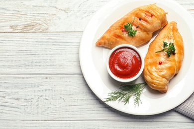 Photo of Plate with fried chicken breasts and sauce on wooden background, top view. Space for text