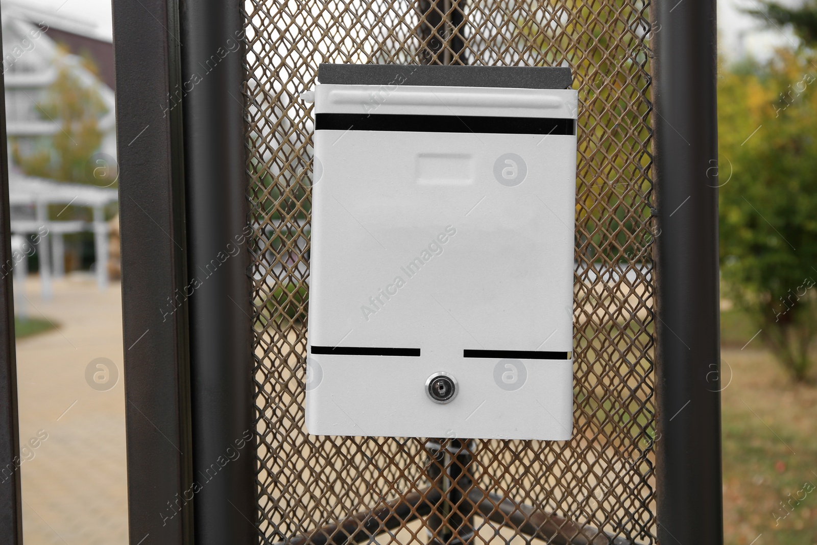 Photo of White metal letter box on fence outdoors