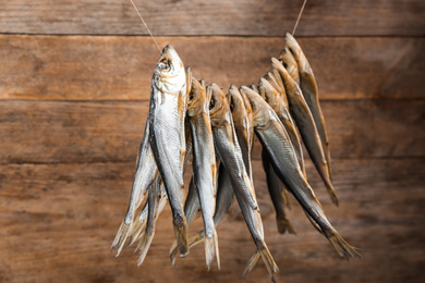 Photo of Dried fish hanging on rope against wooden background