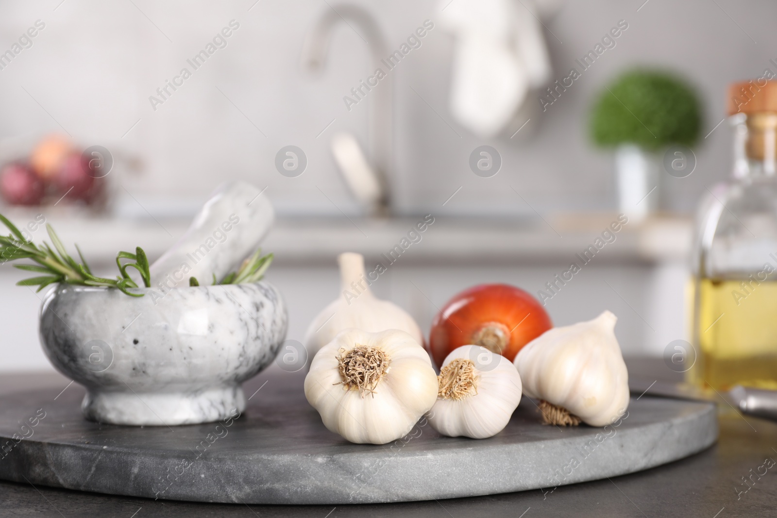 Photo of Fresh raw garlic, onion and rosemary on grey table, closeup