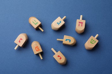 Photo of Wooden dreidels on blue background, flat lay. Traditional Hanukkah game
