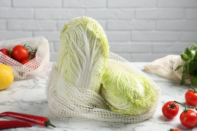 Photo of Fresh Chinese cabbages and other vegetables on white marble table near brick wall