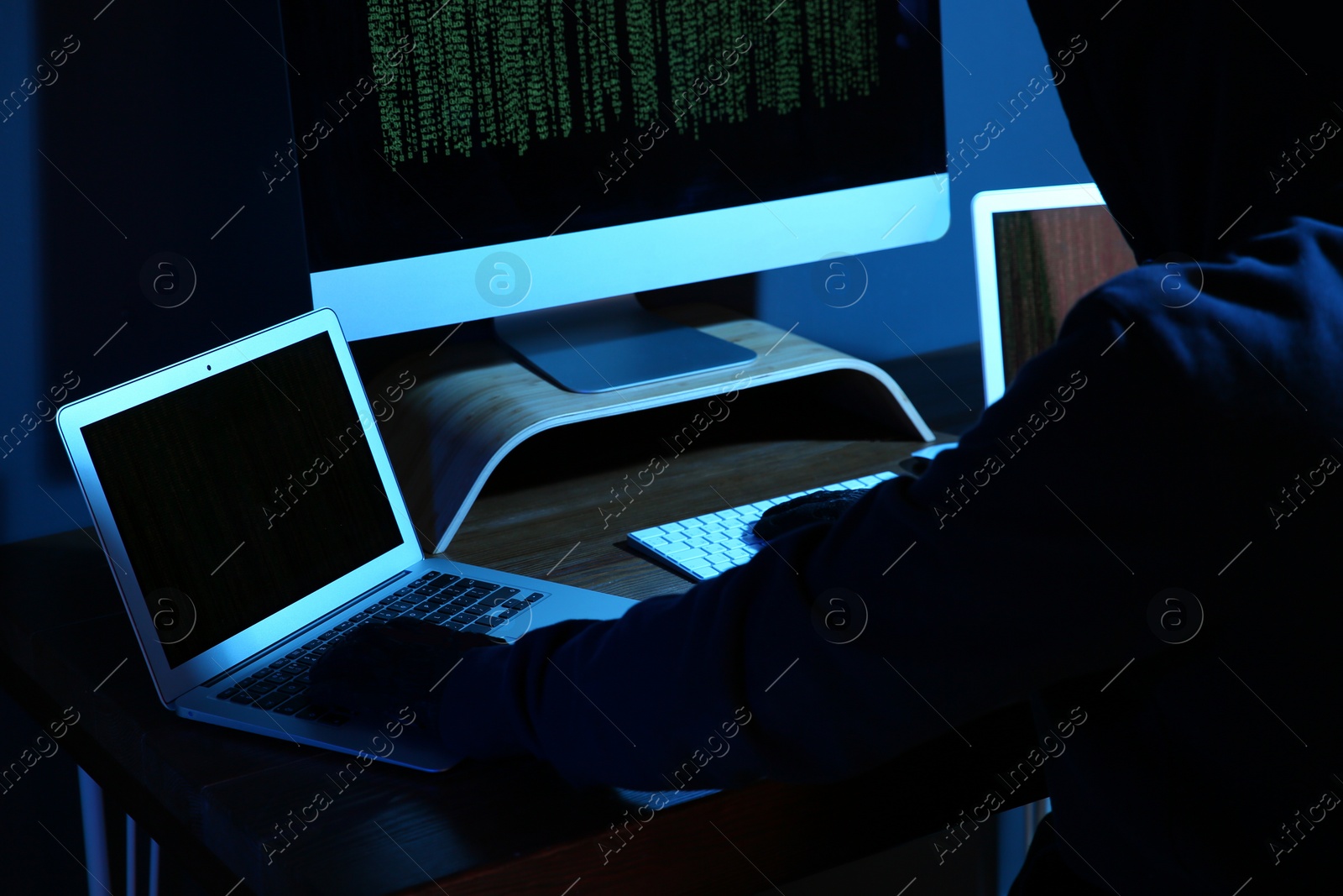 Photo of Hacker with computers in dark room, closeup. Cyber crime