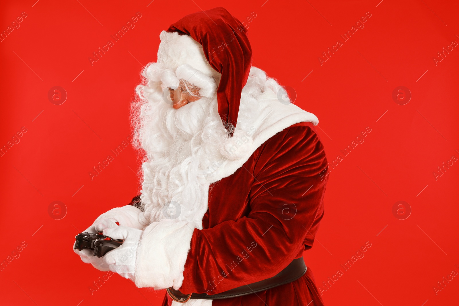 Photo of Authentic Santa Claus with game controller on red background