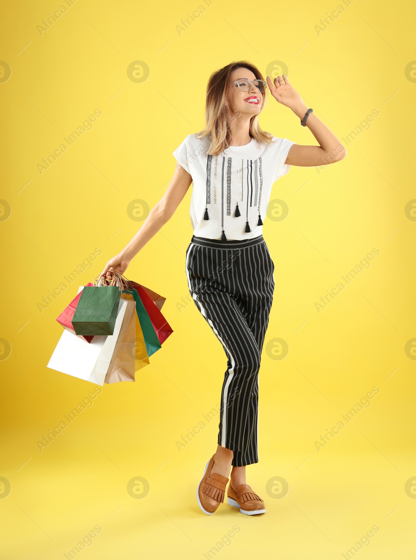 Photo of Beautiful young woman with shopping bags on color background