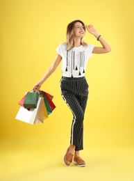 Photo of Beautiful young woman with shopping bags on color background