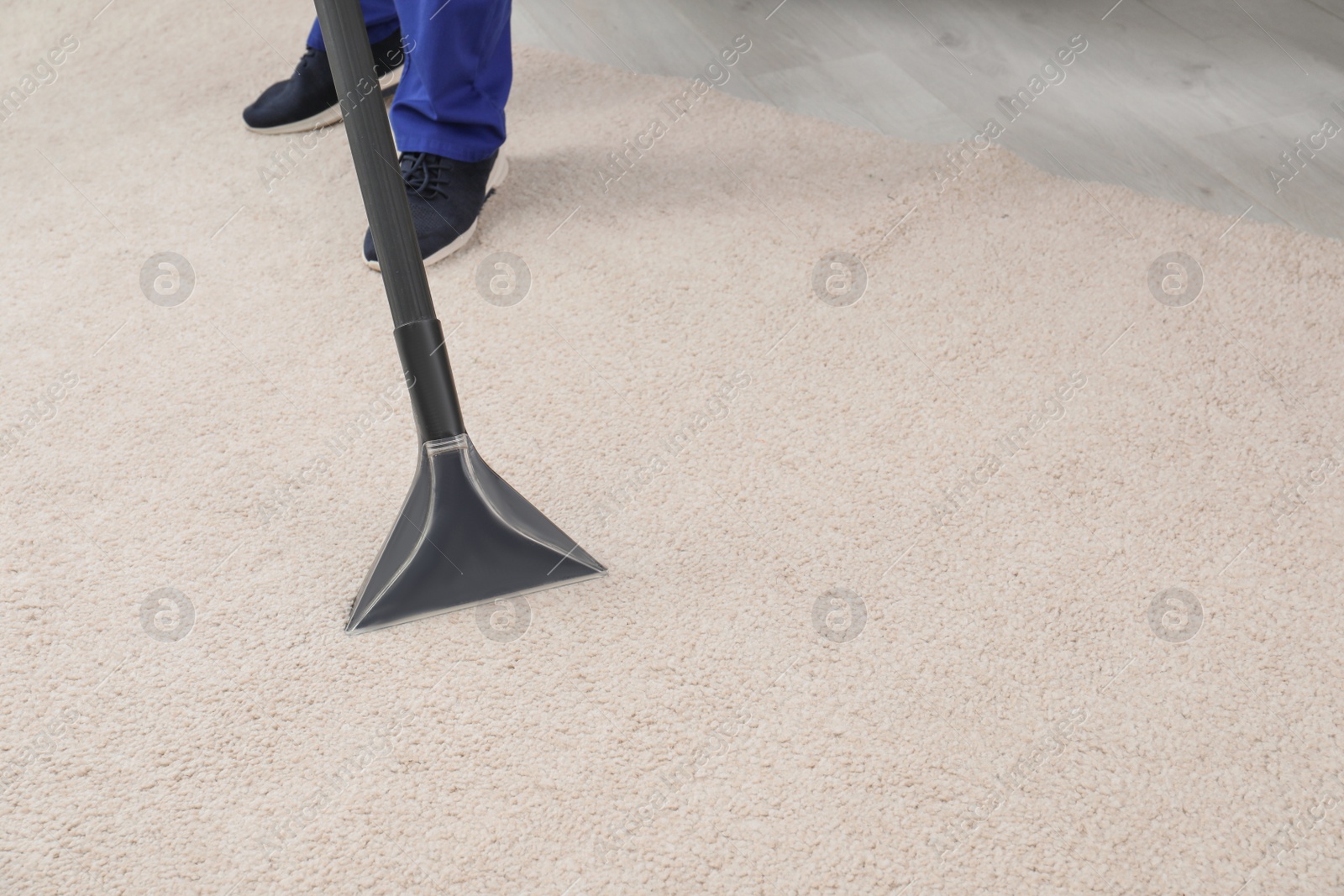 Photo of Man removing dirt from carpet with vacuum cleaner indoors, closeup. Space for text