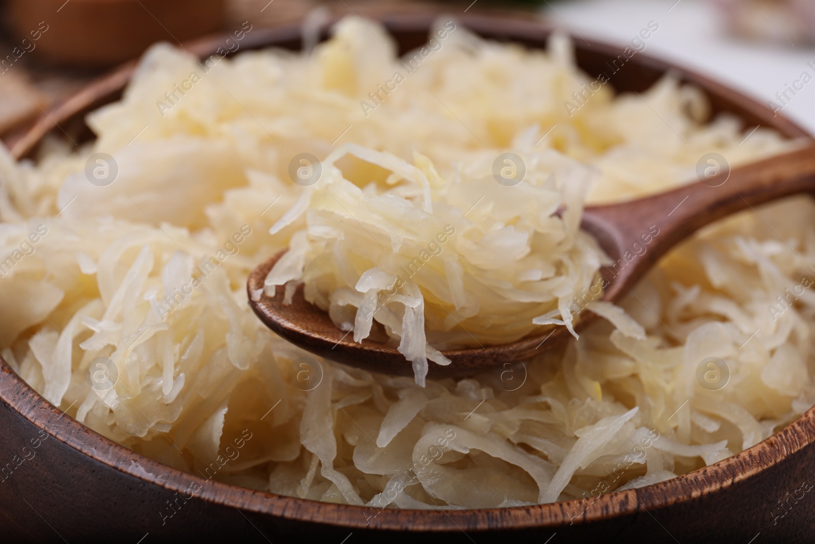 Photo of Spoon and bowl of tasty sauerkraut, closeup view